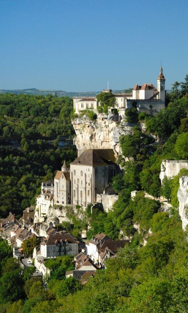 Vista de Rocamadour desde la carretera con vegetación verde y cielo azul