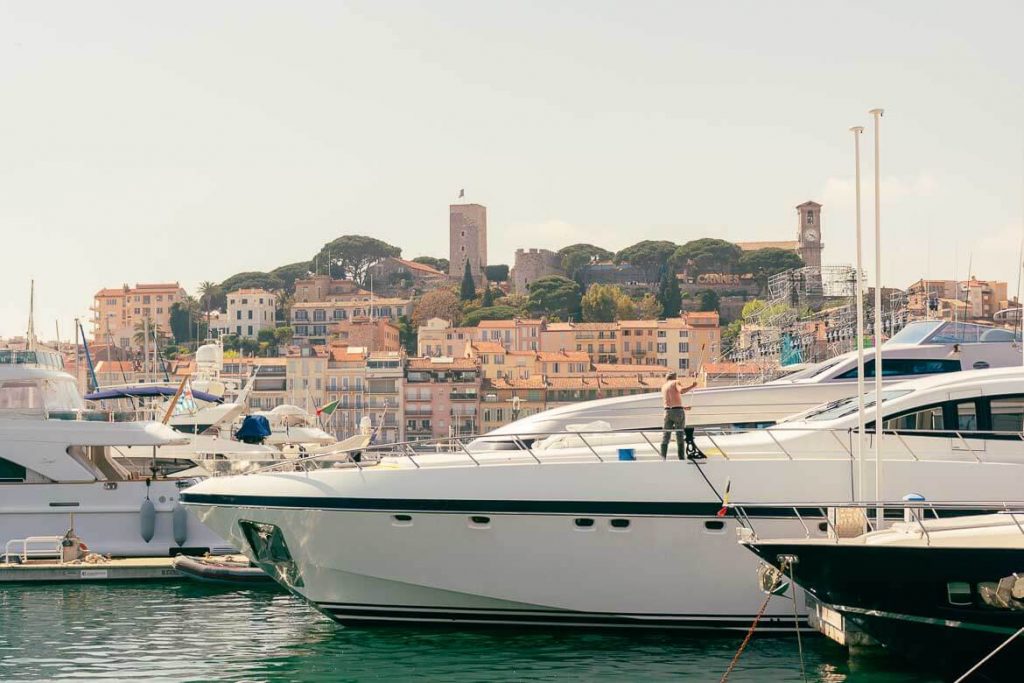A man cleaning a white yacht at the pier of Cannes in the South of France in October