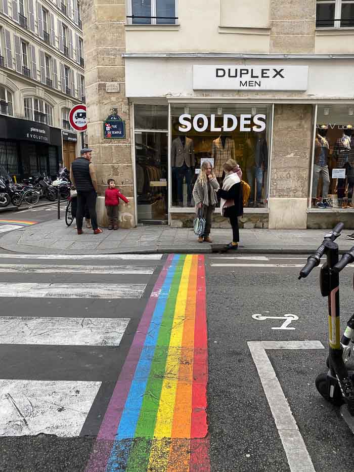 People in Le Marais with people walking along the street filled with shops that are luxurious and affordable to save France budget