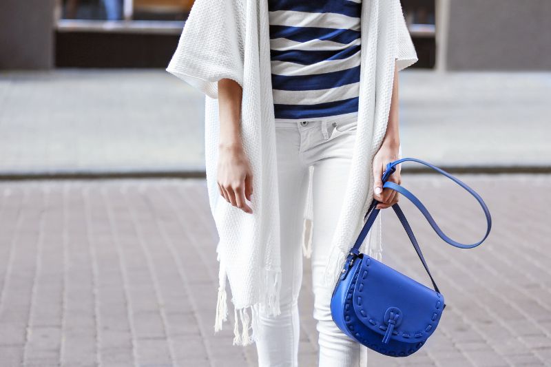 mujer con un bolso azul y ropa blanca