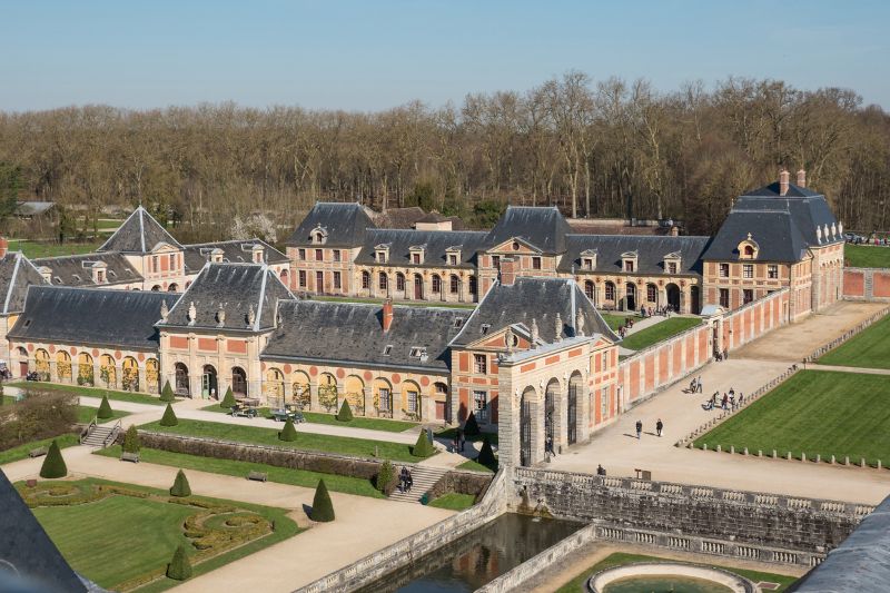 Aerial view of the Vaux-Le-Vicomte with people visiting and trees at the back with no leaves indicating Paris in winter