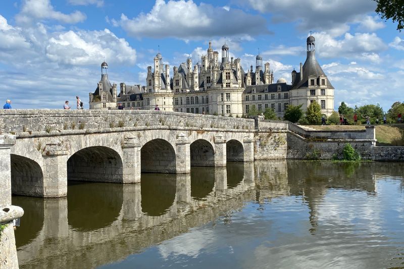 A bridge leading to the Chambord Castle under cloudy skies. It is one of the Loire Valley Castles to visit!
