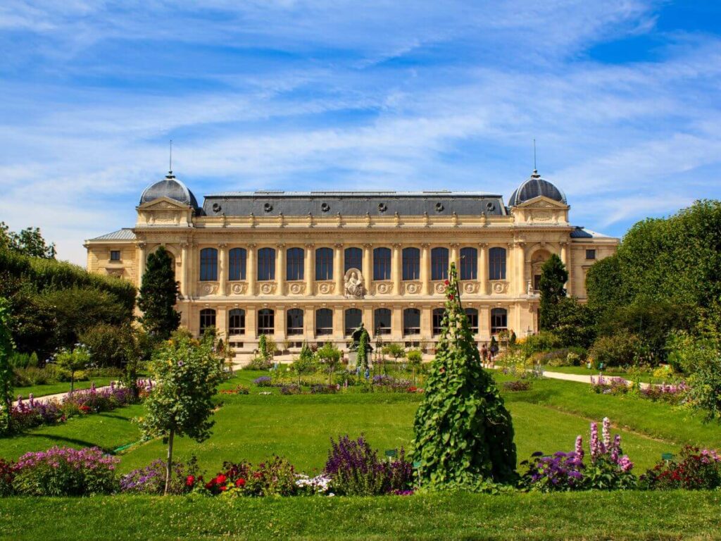 Jardin des Plantes Park with a building of the Grande galerie de l'évolution at the back under bright blue skies in Paris in November