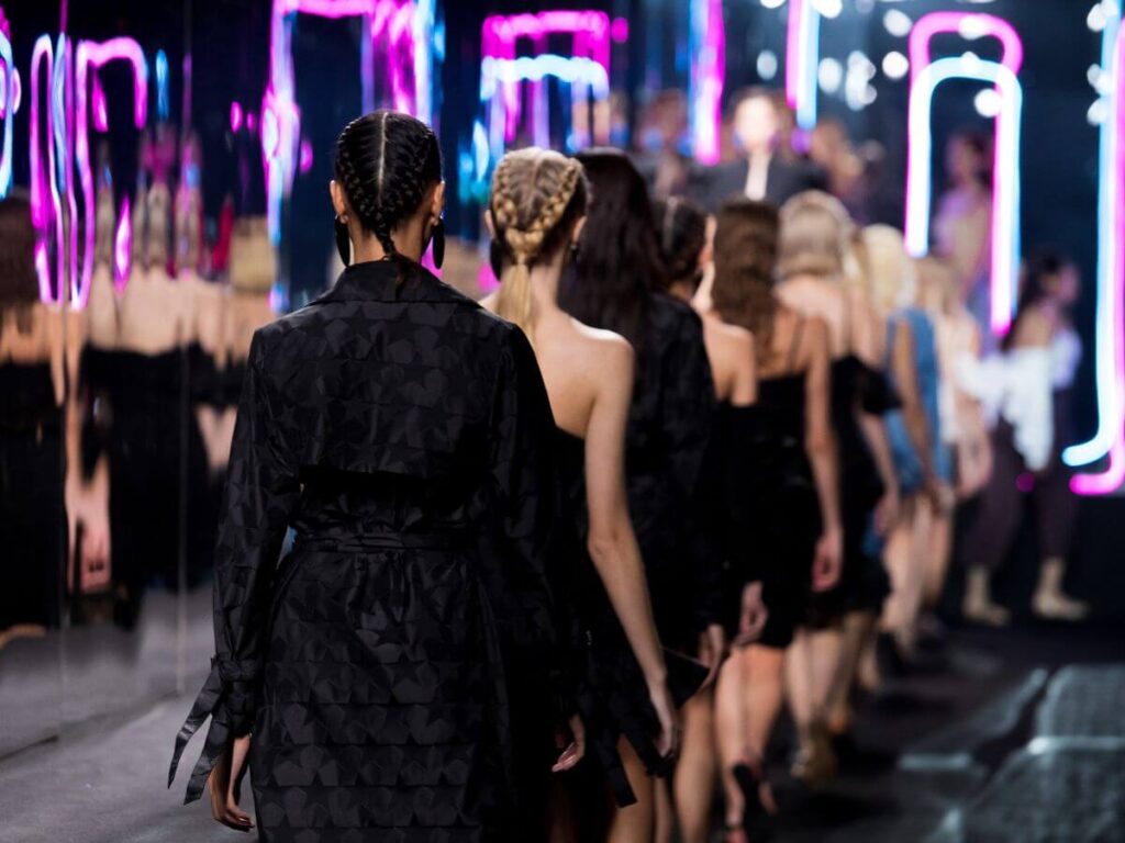 Models walking in black dresses during the Paris Fashion Week in October