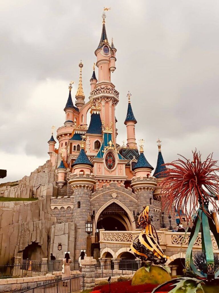 Entrada del castillo rosa de Disneyland París bajo nubes oscuras en noviembre