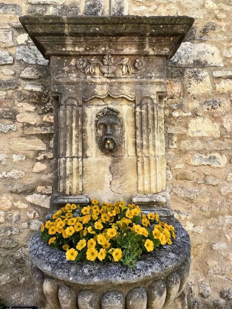 Medieval fountain with yellow flowers